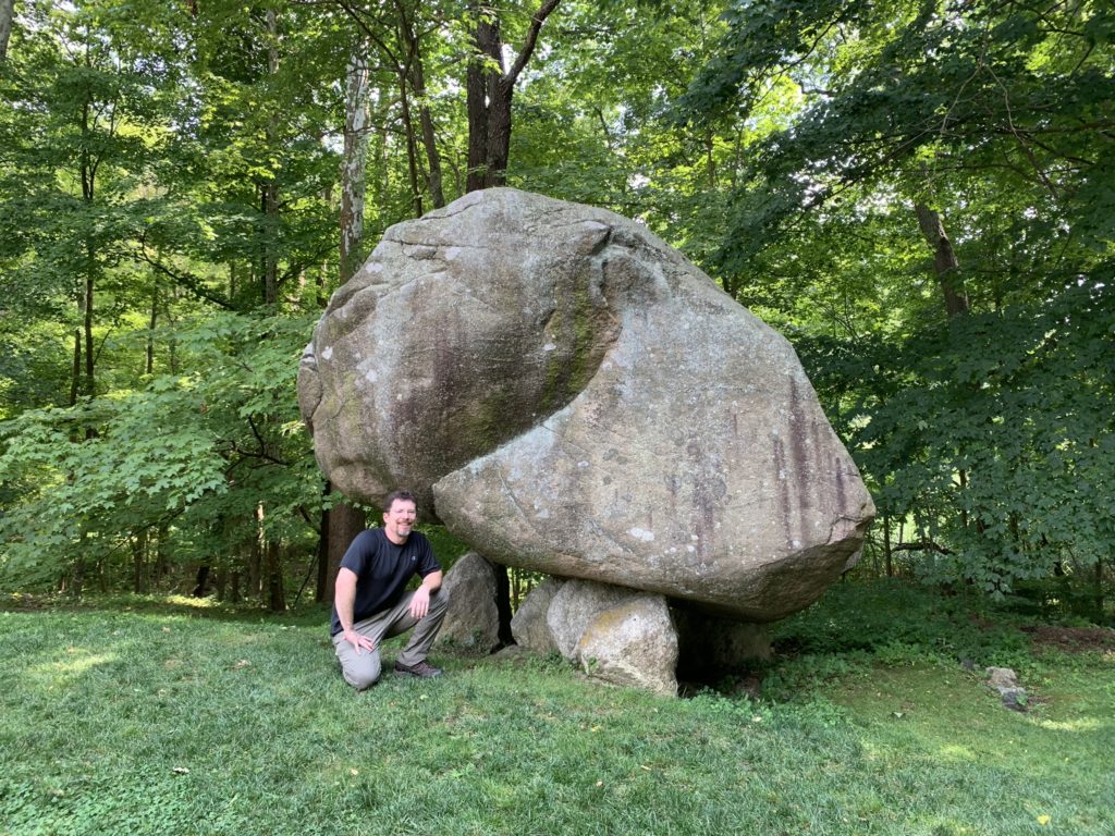 Wade Boman kneeling with Balanced Rock, North Salem, NY